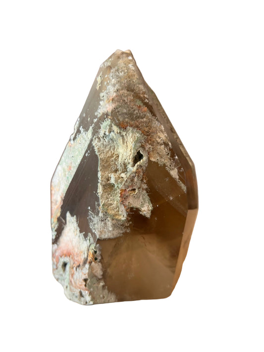 A raw, rough-cut crystal point mineral specimen with a brownish-gray translucent body and white crystalline matrix, resting on a light wood surface.